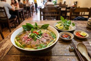 A steaming bowl of authentic Vietnamese pho bo with beef broth, rice noodles, fresh herbs, and lime at Vietnam Palace Restaurant Ottawa